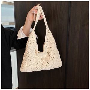 Detailed view of hand-crocheted hollow floral pattern on a beige knit shoulder bag