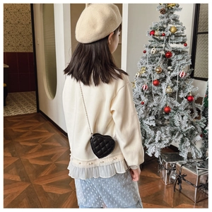 Détail du sac coeur noir matelassé avec bandoulière chaîne sur une tenue de fête enfant