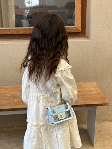Fille en robe de dentelle avec sac gelée bleu clair transparent et chaîne de perles