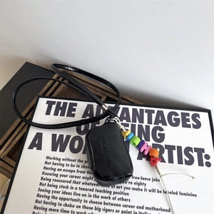 Close-up of black glossy mini bag with colorful letter beads and embossed details