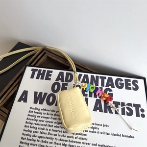 Detail of mini yellow leather coin purse with embossed letters and colorful beaded strap