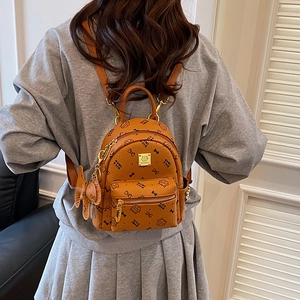 Mini brown cartoon bear backpack with gold logo plate shown on model from back view