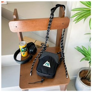 Mini sac bandoulière noir et à carreaux pour enfant posé sur une chaise en bois