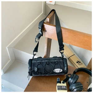 Détail du sac à bandoulière cylindrique noir en nylon avec cordon techwear et sangle