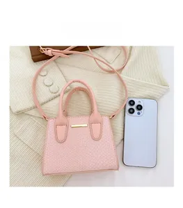 Macro detail of pink snakeskin pattern handbag next to a smartphone for size reference