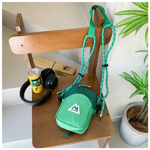 Gros plan sur le sac bandoulière en nylon vert à carreaux avec logo de montagne