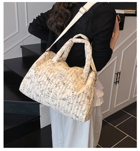 Floral quilted diaper bag with round handle and adjustable strap shown on model