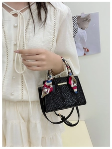 Detail of black faux leather mini bag with snake pattern, silk scarf, and gold accent