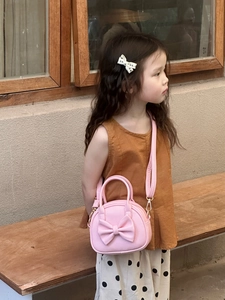 Détail du sac à main rose pour filles avec nœud 3D et bandoulière sur un modèle enfant