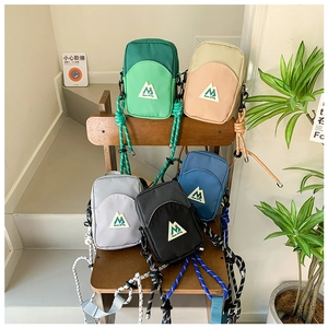 Détail de cinq mini sacs à bandoulière colorés avec sangles tissées sur une chaise en bois