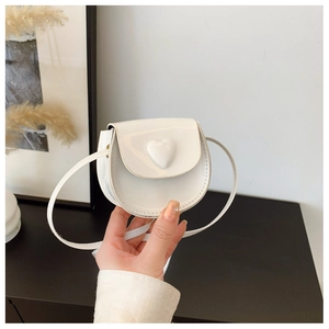 Close-up of a white mini heart-shaped crossbody bag with glossy patent leather finish