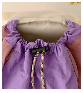 Detail of drawstring closure on purple and pink nylon travel backpack with cord lock