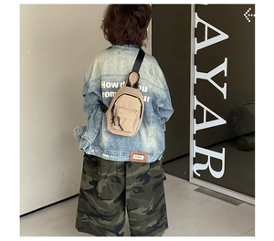 Vue de dos d'un enfant portant un sac de poitrine en toile beige avec bandoulière réglable