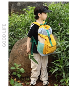 Outdoor view of a color-block kids backpack with pockets on an Asian boy model