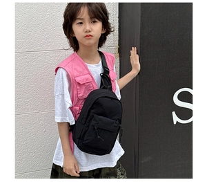 Sac de poitrine en toile noire pour enfants avec poche zippée porté par un enfant