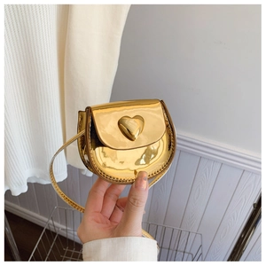 Detail of micro heart-shaped crossbody bag featuring a shiny gold mirror metallic finish