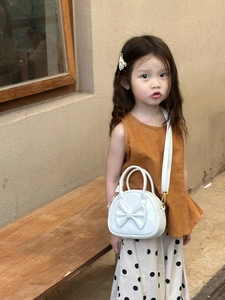 Fille portant un sac à main blanc avec nœud papillon et bandoulière réglable en extérieur