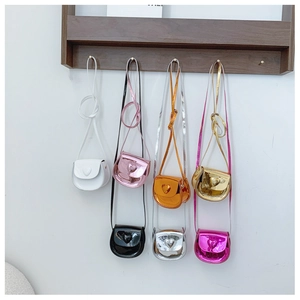 Multiple mini heart bags in metallic colors hanging on a wooden rack for kids