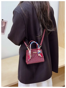 Detail of wine red mini bag with snake pattern texture and silk scarf wrapped handle