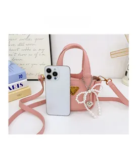 Dettaglio della mini borsa rosa con fiocco di perle, mostra dimensioni compatte con telefono