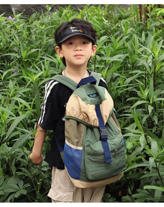 Kids outdoor backpack in green and blue patchwork shown in a natural forest setting