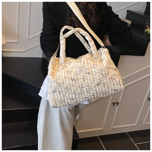 Detailed back view of a quilted floral diaper bag with dual straps on a model