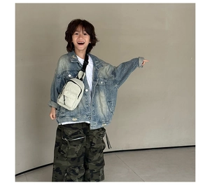 Détail d'un sac de poitrine blanc en nylon avec veste en jean et pantalon camouflage