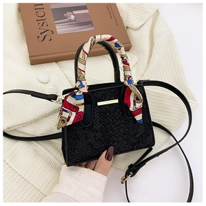 Close-up of black stone pattern handbag with silk scarf handle and golden metal accents