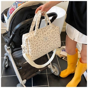 Floral quilted mummy bag with wide shoulder strap hanging on a stroller handle