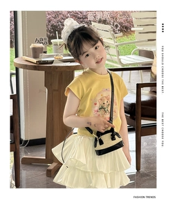 Fillette avec mini sac bandoulière en paille et bordure noire en extérieur ensoleillé