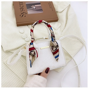 Detailed macro view of cream snakeskin embossed mini bag with decorative twilly scarf handle