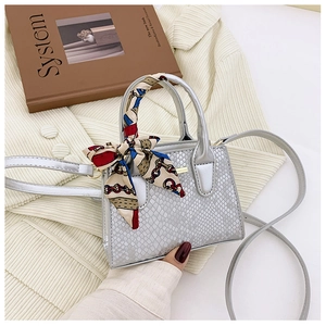 Detailed close-up of silver snake pattern handbag with decorative silk scarf handle