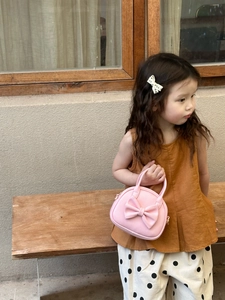 Sac à main rose pour fille avec grand nœud présenté dans un décor extérieur doux