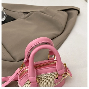 Vue macro du mini sac en paille montrant les poignées en cuir rose et la texture tissée