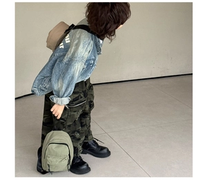 Détail du sac de poitrine en toile olive avec pantalon camouflage et veste en jean
