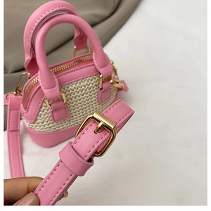 Détail de cuir rose et texture tissée beige sur un mini sac avec boucle dorée