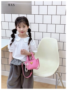 Dettaglio della mini borsa rosa con fiocco di perle e logo in metallo su bimba