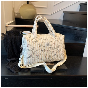 Detail of floral quilted diaper bag with adjustable shoulder strap and sturdy handles