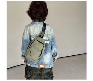 Détail du sac de poitrine en toile vert clair pour enfants avec sangle noire réglable