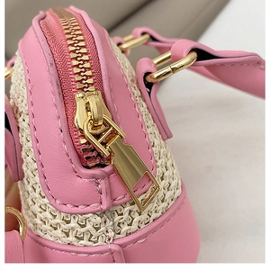 Détail de la bordure en cuir rose et fermeture éclair dorée sur sac en paille