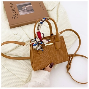 Detailed view of a brown faux crocodile leather handbag with a silk scarf handle