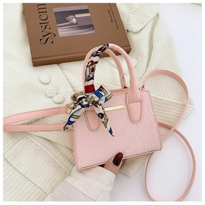 Detailed view of pink snake-print mini bag with scarf-wrapped handle and gold trim