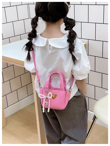 Dettaglio mini borsa a tracolla rosa per bambini con ciondolo a fiocco di perle