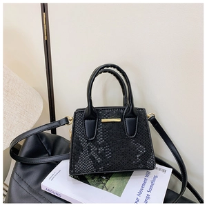 Detail shot of black snake pattern handbag with gold hardware on a magazine