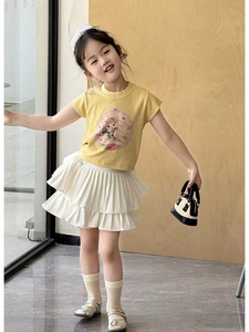 Détail de la tenue d'été pour enfant avec t-shirt jaune gingembre et jupe plissée blanche