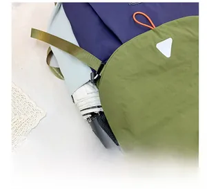 Detail of outdoor kids backpack side mesh pocket holding a black folding umbrella