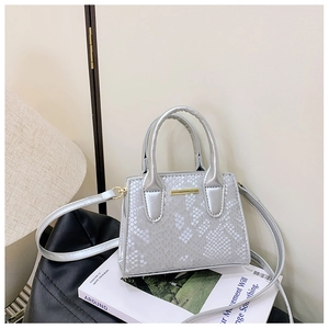 Detail of silver embossed faux leather tote bag with gold metal trim and round handles