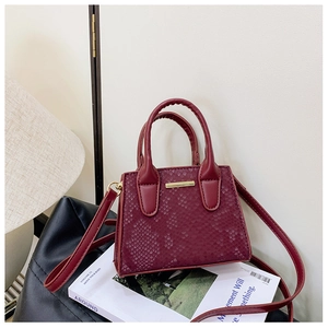 Close-up of wine red embossed leather bag with golden hardware and snakeskin texture