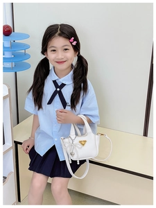 Dettaglio borsa bianca per bambina in pelle con fiocco di perle e placca triangolare d'oro
