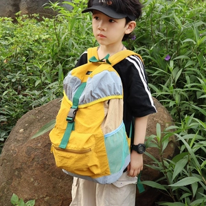 Kids large yellow nylon backpack with green straps shown on a child in nature